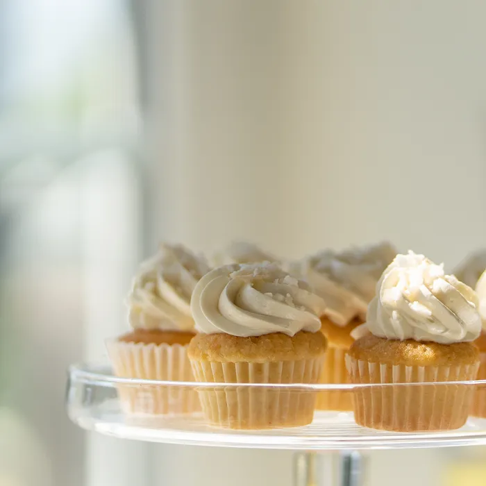 Vanilla cupcakes with frosting on a glass cake stand
