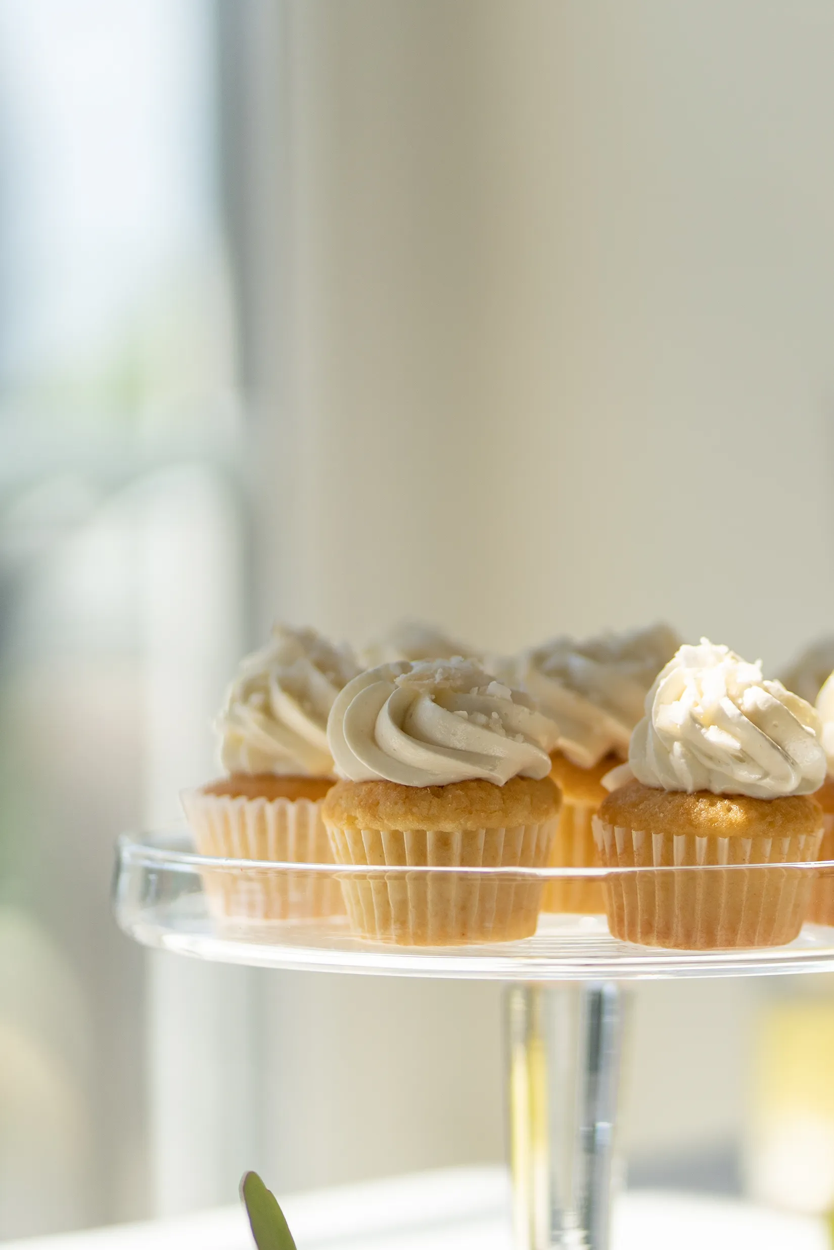 Vanilla cupcakes with frosting on a glass cake stand